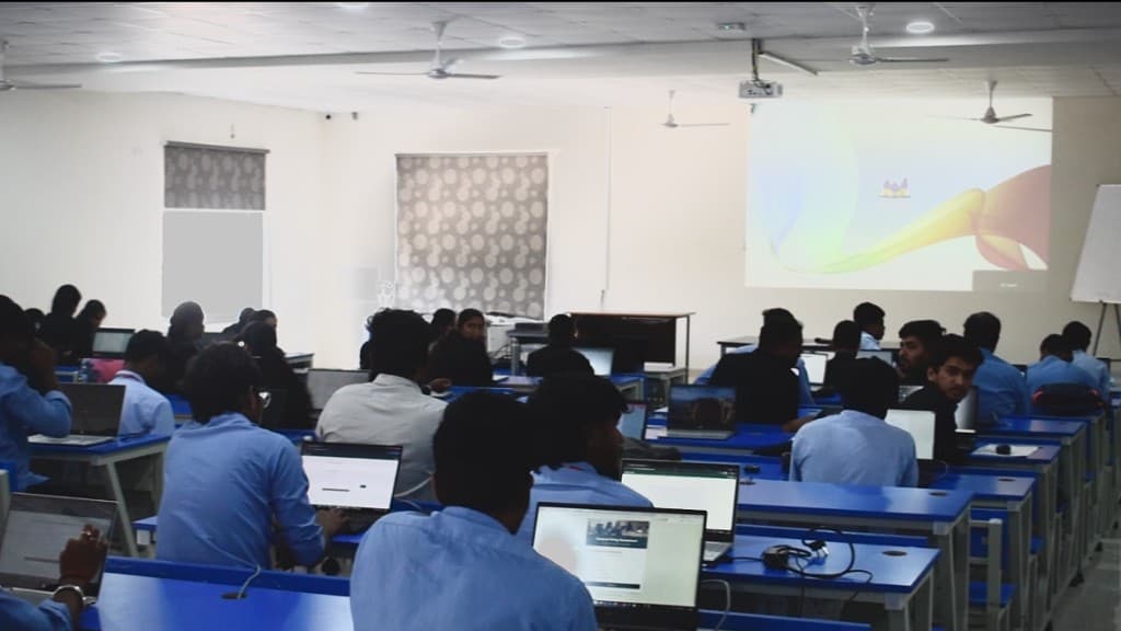 The Syncpedia lab during a session, laptops open and a lesson on the screen